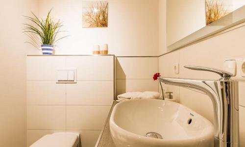 a white bathroom with a sink and a toilet at Darßzeit in Ahrenshoop