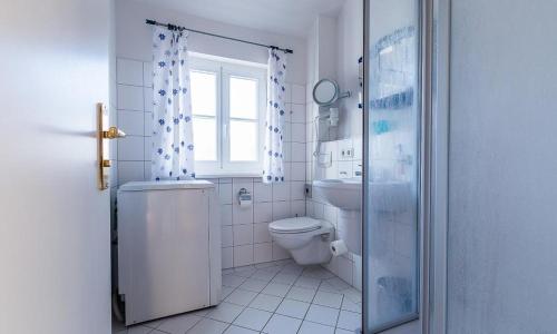 a white bathroom with a toilet and a window at Madlen in Ahrenshoop