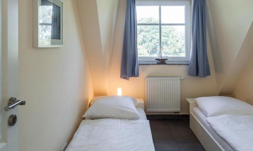 two beds in a small room with a window at Boddenzauber 02 in Wieck