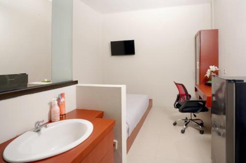 ein Bad mit einem Waschbecken und einem Schreibtisch mit einem Stuhl in der Unterkunft DPARAGON SUMBER in Solo
