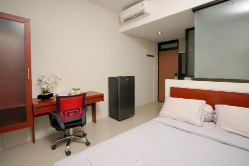 a bedroom with a bed and a desk and a chair at DPARAGON SUMBER in Solo