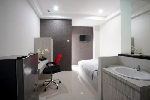 uma casa de banho com um lavatório, uma cama e uma cadeira. em DPARAGON KALIJUDAN em Surabaya