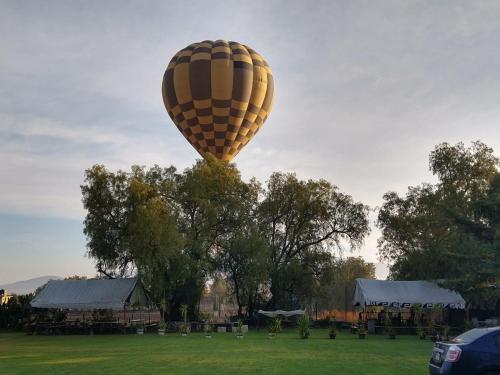 a hot air balloon is flying over a field at Telpochcalli Hotel & Temazcal in San Juan Teotihuacán