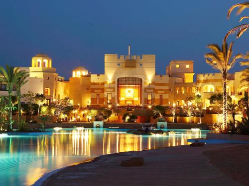 a large building with a pool in front of it at night at Pickalbatros The Palace Port Ghalib in Port Ghalib