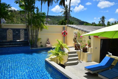 a house with a swimming pool with a green umbrella at Angelot Villa in Chaweng Noi Beach