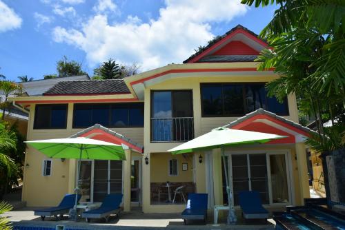 a house with two green umbrellas in front of it at Angelot Villa in Chaweng Noi Beach