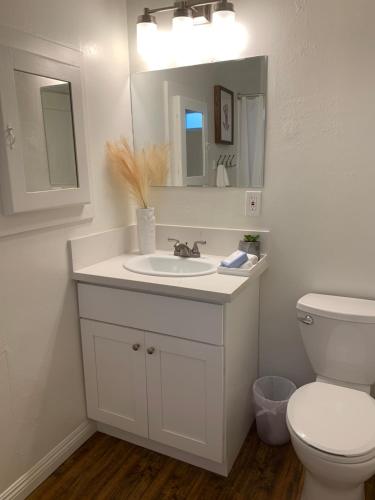 un bagno con lavandino, WC e specchio di Huntington Highlight - Pool, Patio, Close To Beach a Huntington Beach