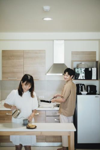 a man and woman preparing food in a kitchen at Palm Crescent Hua Hin in Cha Am