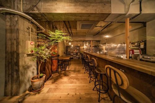 un restaurante con un bar con mesas y sillas en ArtBar & GuestHouse ennova, en Atami