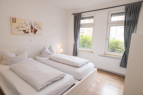 two beds in a white room with windows at FeWo Engler Lüneburg Gellersstraße in Lüneburg