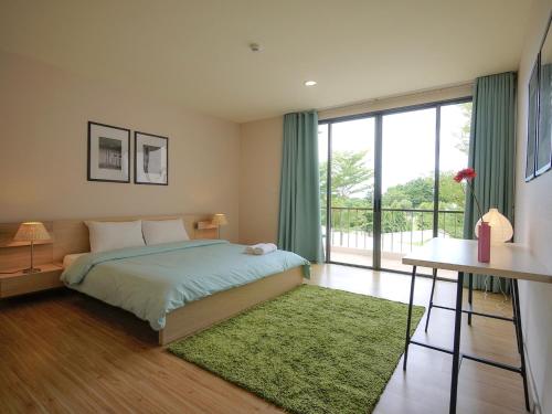 a bedroom with a bed and a large window at Palm Crescent Hua Hin in Cha Am