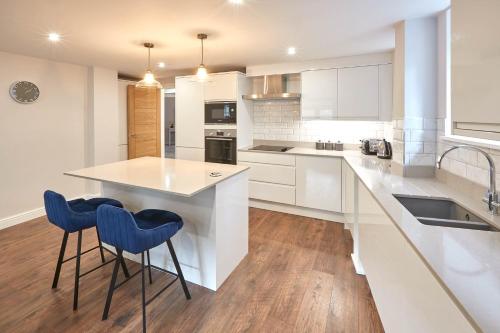 a kitchen with white cabinets and blue bar stools at Host & Stay - The Garden Apartment in Harrogate