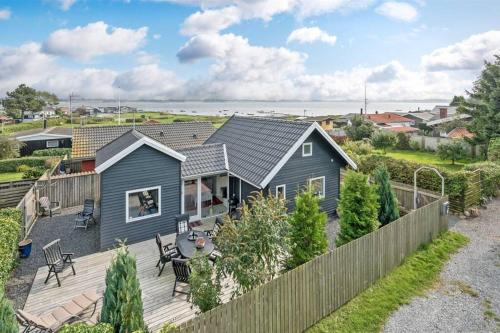 a small blue house with a wooden deck at Skøn feriebolig med havudsigt i naturskønt område in Munkebo