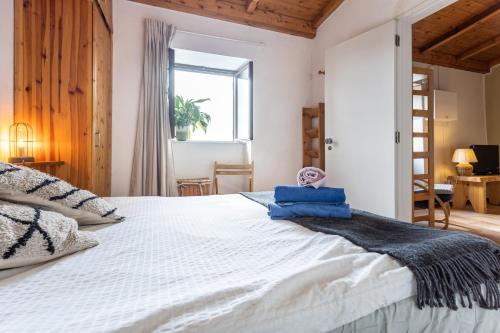 - une chambre avec un grand lit blanc et des serviettes bleues dans l'établissement Cottage in historical town of Aljezur, à Aljezur
