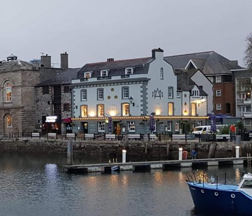 un grand bâtiment à côté d'une étendue d'eau avec un bateau dans l'établissement The Three Crowns B&B, à Plymouth