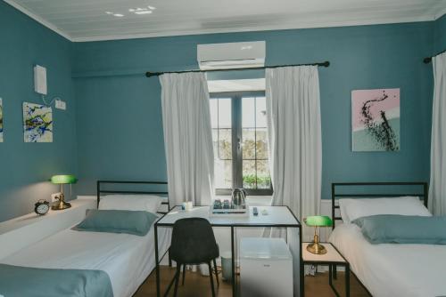 a bedroom with two beds and a table and a window at Atelier Boutique Hotel in Shkodër