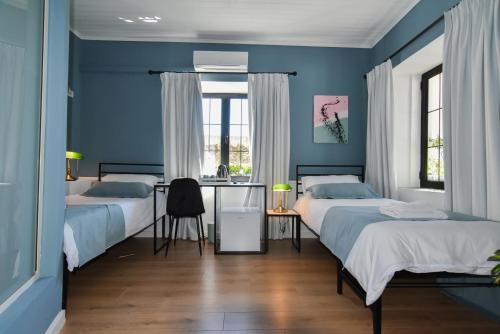 a blue bedroom with two beds and a desk at Atelier Boutique Hotel in Shkodër