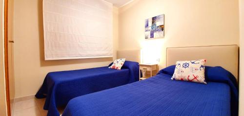 2 Betten in einem Zimmer mit blauer Bettwäsche in der Unterkunft Sueño de Denia III VAC007 Denirent in Denia