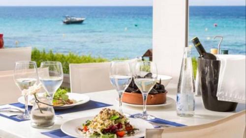 ミハス・コスタにあるMI CAPRICHO BEACHFRONT- P301 Apartment with sea viewのテーブル(一皿の食べ物とワイングラス付)