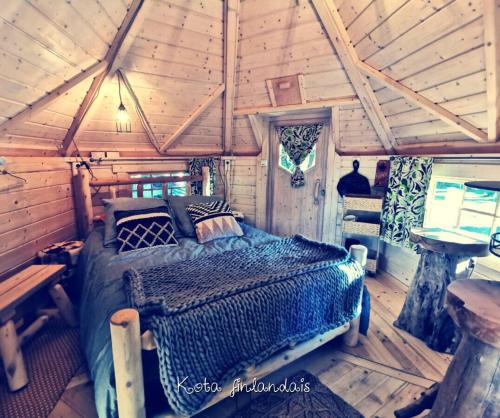 a bedroom of a log cabin with a bed in it at Juste par hasard chambres d hôtes insolites à 140 m de la mer in Saint-Michel-Chef-Chef