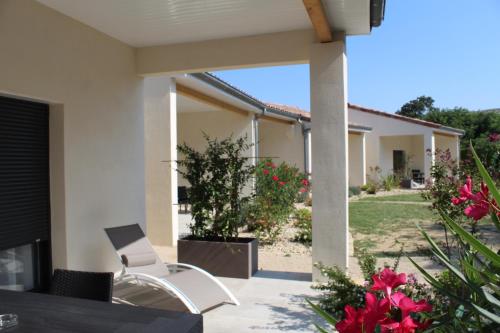 a patio of a house with a chair and flowers at Le Logis de Bérianne in Les Tourrettes