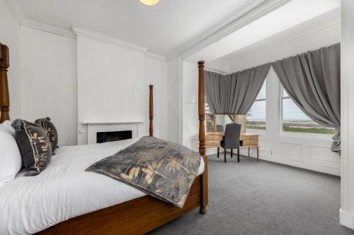 a bedroom with a bed and a desk and windows at Muncaster Cottages in Ravenglass