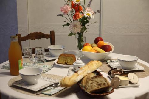 una mesa con un plato de pan y un bol de fruta en Chambre d hote La Roussiere en Saint-Ouen-des-Toits