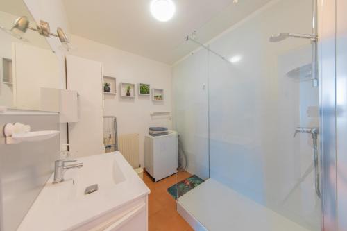 a white bathroom with a shower and a sink at Résidence Clemenceau 1 in Royan