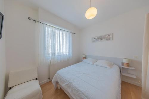 a white bedroom with a bed and a window at Résidence Clemenceau 1 in Royan