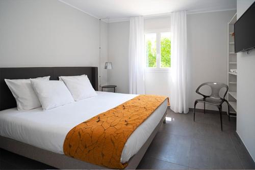 una camera con un letto e una sedia e una finestra di Residence Saletta Casale a LʼÎle-Rousse