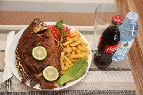 a plate of fish and french fries and a bottle of soda at Harts Motel in Kampala