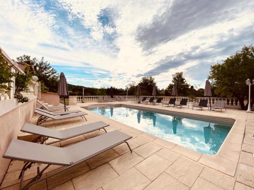 una piscina con tumbonas y sombrillas en La Villa des Ames Liées, en Draguignan
