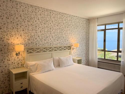Hotel Playa de Los Locos في سوانسيس: غرفة نوم بسرير ابيض ونافذة