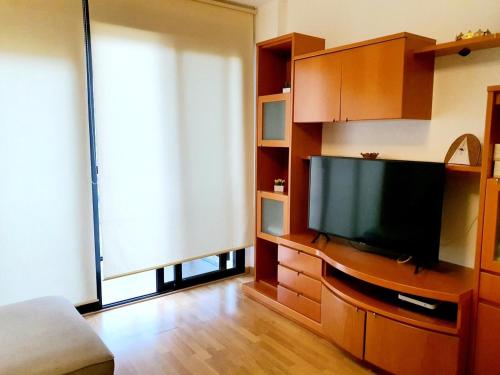 uma sala de estar com uma televisão de ecrã plano num centro de entretenimento em Apartamento ideal para familias em Valência