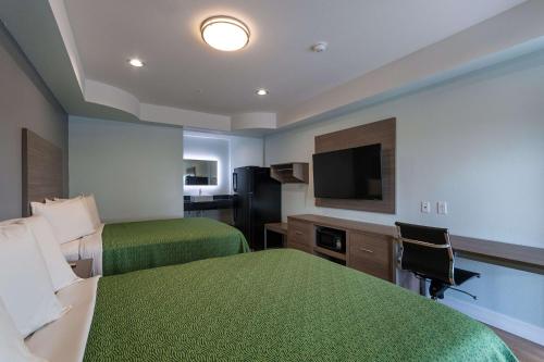 a hotel room with two beds and a flat screen tv at Baymont by Wyndham Kingwood in Kingwood