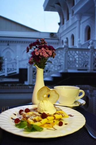 a plate of food on a table with a vase with flowers at The Shahar in Tashkent