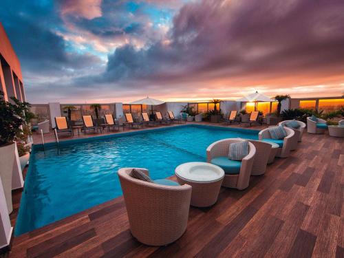a large swimming pool with chairs and a sunset at Mövenpick Hotel Casablanca in Casablanca