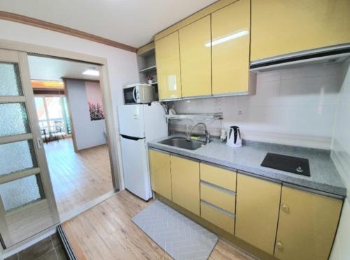 a kitchen with yellow cabinets and a white refrigerator at Namhae Manheim pension in Namhae