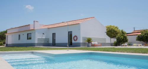 a villa with a swimming pool in front of a house at Flamboyant Boutique B&B in Caldas da Rainha