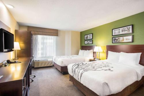 a hotel room with two beds and a television at Sleep Inn Kansas City International Airport in Kansas City