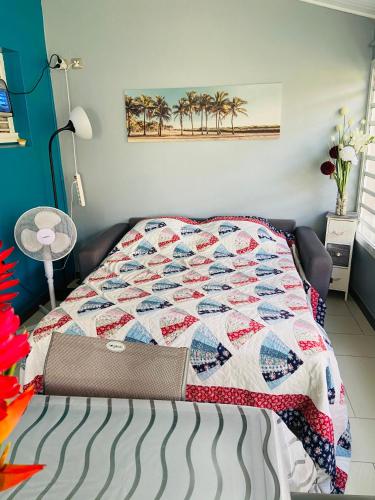 a bed with a quilt on it in a room at Maelya House in Sainte-Anne