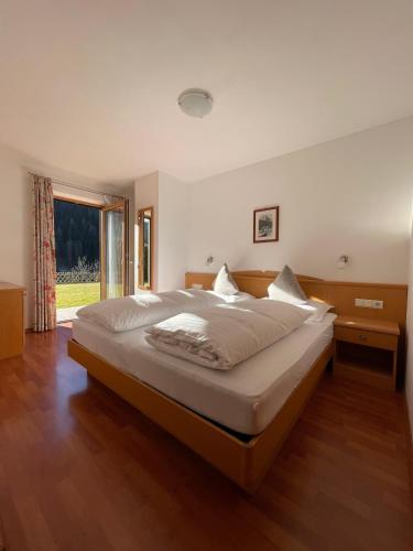 a bedroom with a large bed and a large window at Appartamenti Hetty in Santa Cristina Gherdëina