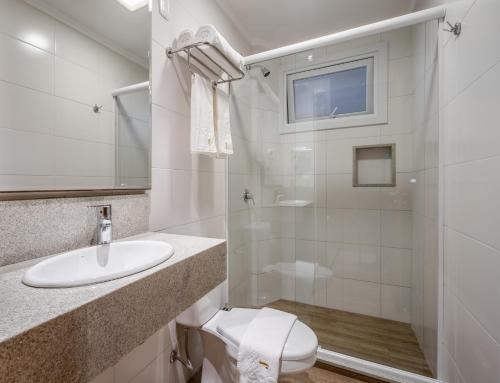 a bathroom with a toilet and a sink and a shower at Hotel Fioreze Centro in Gramado