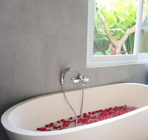eine Badewanne mit roten Blumen im Bad in der Unterkunft Stana Kendran Villa in Ubud