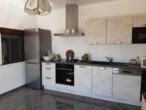 - une cuisine avec des placards blancs et une cuisinière noire dans l'établissement La Crotinière, à Marmagne