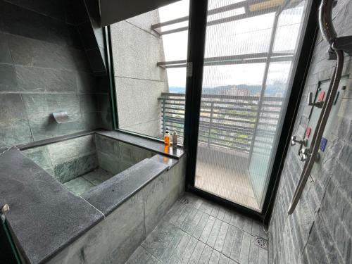 a bathroom with a walk in shower and a window at 山玥溫泉 in Jiaoxi