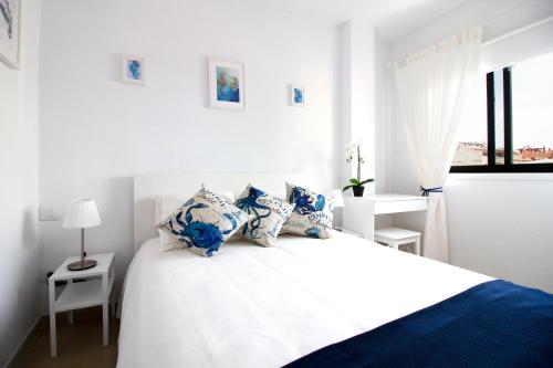 biała sypialnia z łóżkiem z białymi i niebieskimi poduszkami w obiekcie Los Angeles 3 Bed Apartment with Pool w mieście Puerto de Santiago