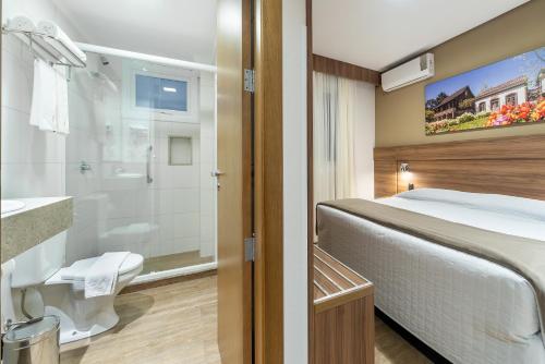 a hotel room with a bed and a bathroom at Hotel Fioreze Centro in Gramado