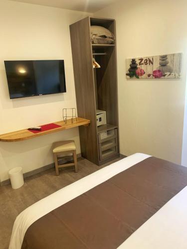a bedroom with a bed and a desk with a television at Hôtel Beau Soleil in Le Lavandou