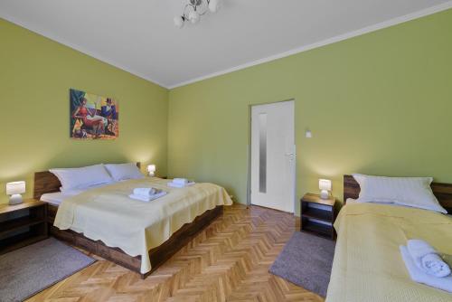 2 Betten in einem Zimmer mit grünen Wänden in der Unterkunft DuMalux corner in Subotica
